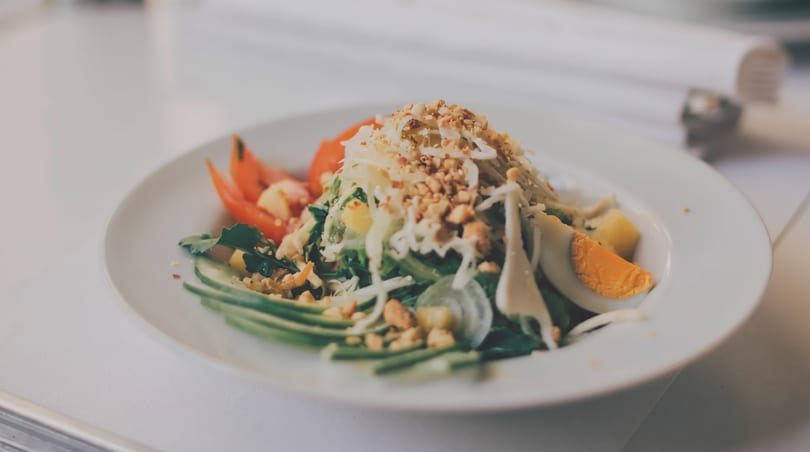 Fresh salad with greens, shredded vegetables, peanuts, avocado, tomato, and hard-boiled egg.